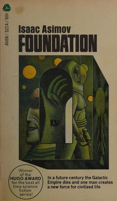 A tan/cream field with a surreal painted illustration of a giant sculpted head in profile with its skull opened like a doorway, through which a small spacesuited astronaut figure walks, set among floating orange discs and a geometric golden structure; "Isaac Asimov" sits in black capitals at the top with "FOUNDATION" in larger bold black capitals below it, "AVON / S224 / 60c" runs in small type up the left edge, a round "Winner of the HUGO AWARD for the best all time science fiction series!" seal sits at lower left, and a black caption box of jacket copy sits at lower right.